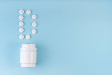 Mavi şişeden D vitamini hapları düştü. Tabletlerden D harfi. D vitamini konsepti. Bağışıklık koruma konsepti, antiviral önleme. Besleyici takviyeler. Üst görünüm, alanı kopyala