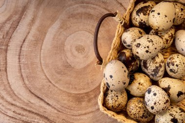 Hasır sepetteki bıldırcın yumurtaları ahşap kesim dokusunda. Kırsal tarzda bıldırcın yumurtası. Mutlu Paskalyalar. Sağlıklı gıda konsepti. Yan kuruluş çiftliğinden doğal organik ürün. Çevre yemeği. Uzayı kopyala, düz yat