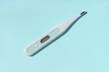 Mavi arka planda tıbbi elektronik termometre. Tıp, sağlık hizmeti kavramı. 