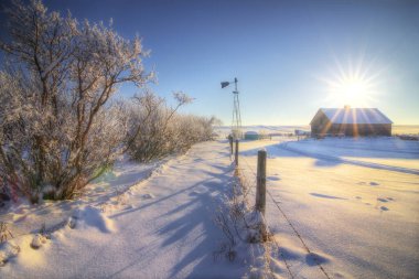 Early morning sunrise over a heritage farm house on the Canadian Prairies after a snow storm. clipart