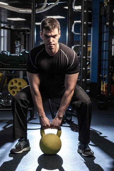 Молодой мускулистый человек тренируется в спортзале — стоковое фото