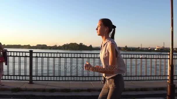 Jovem mulher correndo ao pôr do sol — Vídeo de Stock