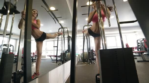 Chica haciendo ejercicio para las piernas en la estación de fitness en el gimnasio . — Vídeos de Stock