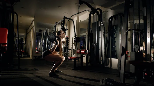 Fille faire squatting avec haltère dans la salle de gym . — Photo