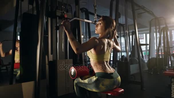 Young woman doing exercise for back on training machine — Stock Video