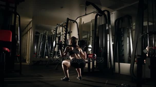 Flicka gör huk med skivstång i gymmet. — Stockvideo