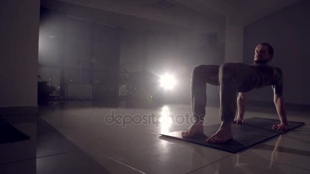 Flexibele man staat op zijn handen in een sportschool. — Stockvideo