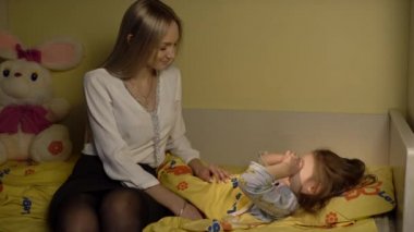 Küçük kızı uyumaya anne koyar.
