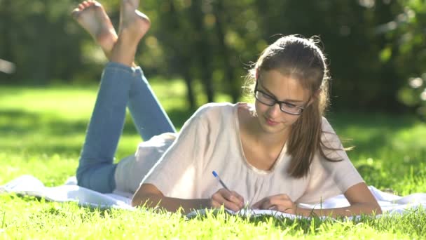 Jovem menina bonita no prado escreve para notebook — Vídeo de Stock