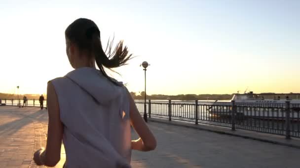 Νεαρή γυναίκα τζόκινγκ στο ηλιοβασίλεμα — Αρχείο Βίντεο