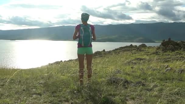 Fiatal nő, hátizsák, kerek hegyek és a tó — Stock videók