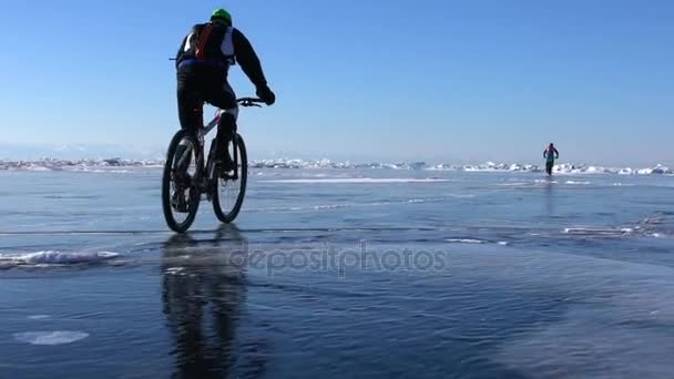 Hombres montando una bicicleta en la superficie del lago congelado — Vídeos de Stock