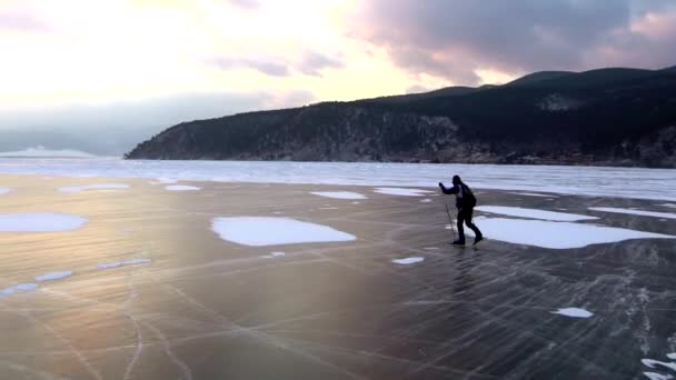 男は美しい日没時に冷凍バイカル湖氷上スケートします。. — ストック動画