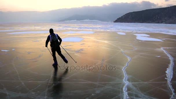 L'homme patinent sur la glace du lac Baïkal gelé pendant le beau coucher de soleil . — Video