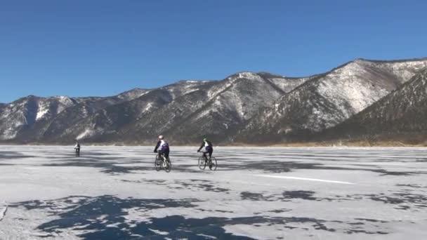 Erkekler donmuş gölün yüzeyinde bir bisiklet sürme — Stok video