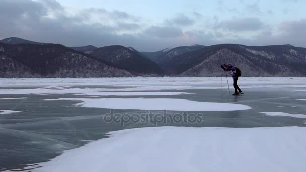 L'homme patinent sur la glace du lac Baïkal gelé pendant le beau coucher de soleil . — Video