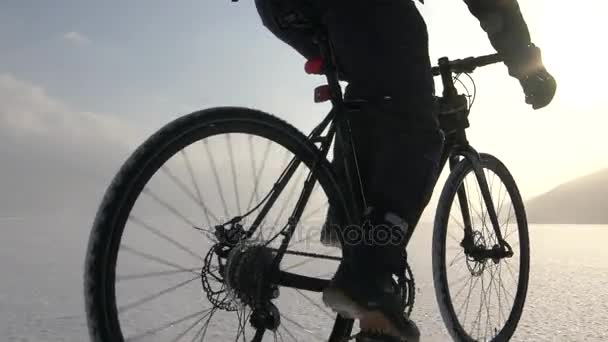 Hombre montando en bicicleta a través de un lago congelado — Vídeos de Stock