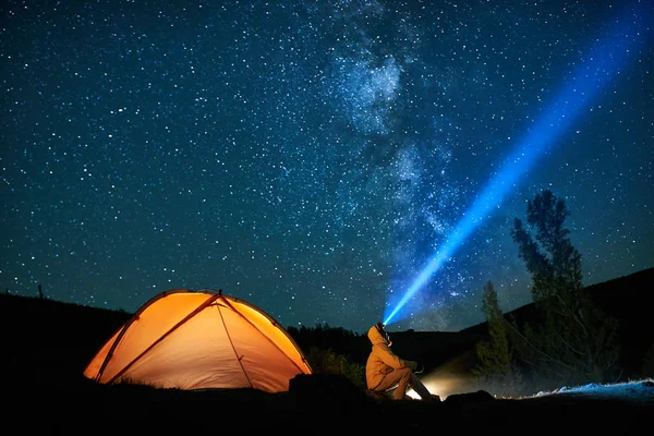 Homem turista com lanterna perto de sua tenda acampamento à noite . — Fotografia de Stock