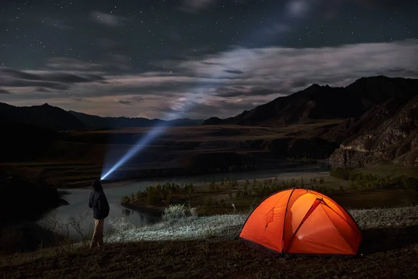 Manliga turist med ficklampa nära sitt camp tält på natten. — Stockfoto