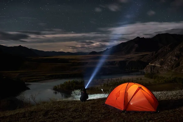 Muž turista s baterkou u stanu tábor v noci. — Stock fotografie