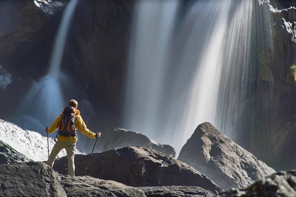Похідний чоловік з рюкзаком дивиться на водоспад — стокове фото