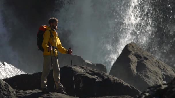 Ein männlicher Wanderer beobachtet einen großen Wasserfall in Zeitlupe. — Stockvideo