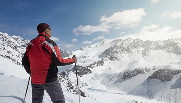 Horolezec v slunný zimní den při pohledu na zasněžené horské krajiny. — Stock fotografie