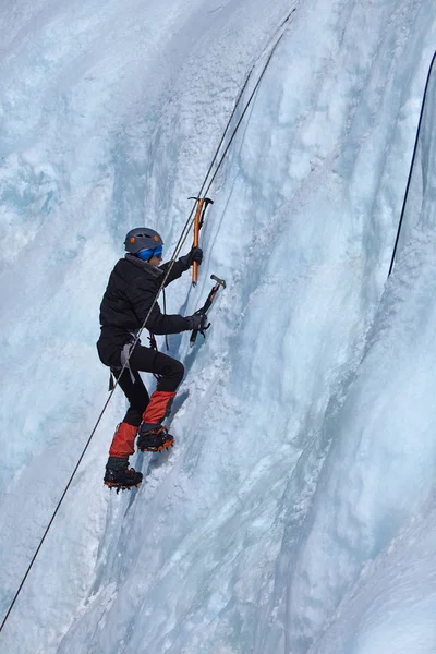 Az ice climber teszi az utat a fagyasztott vízesés. — Stock Fotó