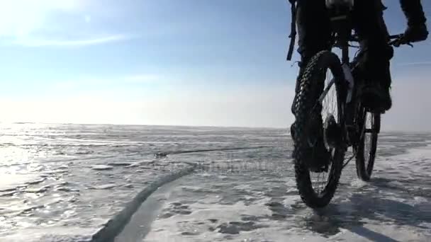 Un hombre montando en bicicleta a través de un lago congelado — Vídeos de Stock