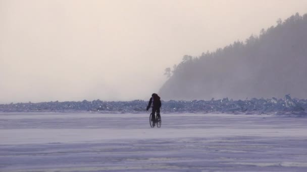 Un uomo in bicicletta attraverso un lago ghiacciato — Video Stock