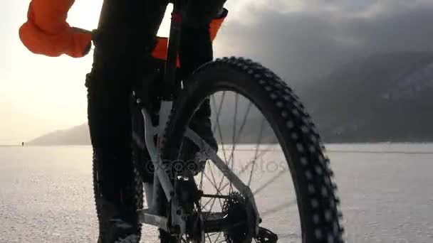 Un hombre montando en bicicleta a través de un lago congelado — Vídeos de Stock