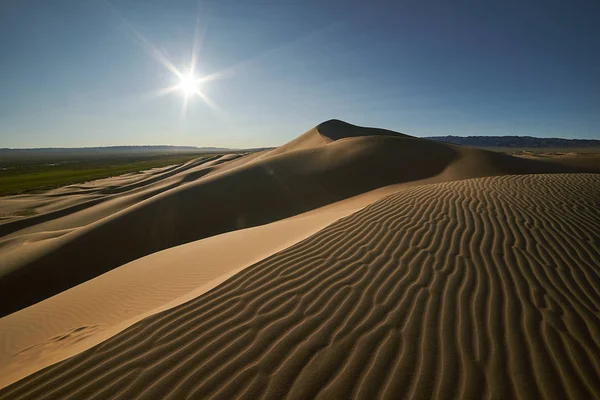Beautiful shot of a desert, wavy sand dunes, shinig sun and blue sky — Stock Photo, Image