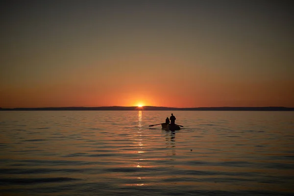 Boat in the sea with two fishermen in it, nets in the sea. Sunset or sunrise — Stock Photo, Image