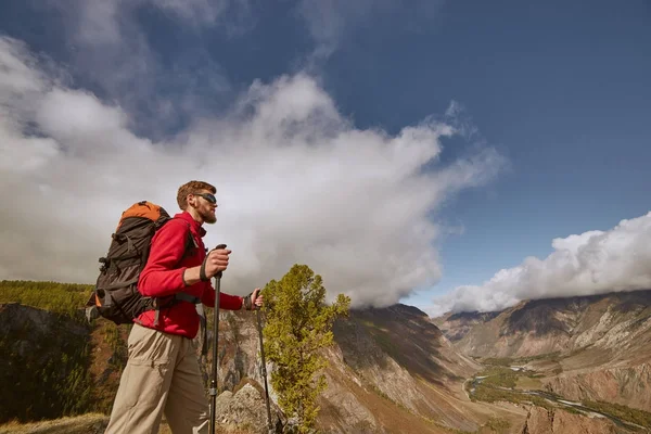 Красивый бородатый молодой турист сидит на краю каньона и смотрит в сторону. — стоковое фото