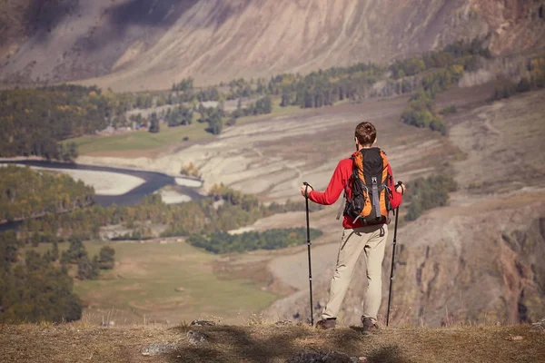 Homem caminhante com postes de trekking e mochila em um topo de uma montanha . — Fotografia de Stock