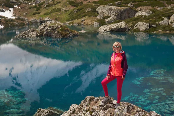 Turistika žena v červené bundě pobyt na krásném jezeře v horách. Stock Snímky