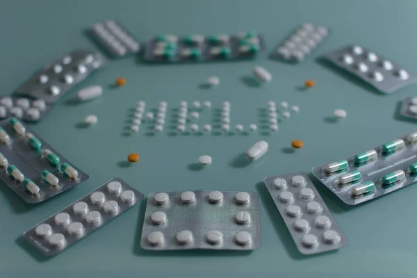 Bir sürü gevşek hap ve yeşil cam sehpanın üzerinde tam tabletler. Diğer günlük ilaçlar.