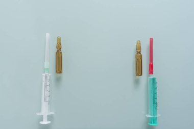 Yeşil arka planda iki şırınga ve iki ilaç kutusu.