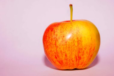 Soluk pembe arka planda izole edilmiş kırmızı elma. 