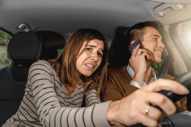 Genç adam araba sürerken telefonla konuşuyor ve kadın yolcu bir engelden kaçınmak için direksiyonu tutuyor. Korkmuş ve çığlık atan çift araba kazası geçiriyor..