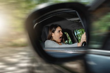 Araba süren ve bağıran genç bir kadın kazadan korkuyor. Görüntü yan aynaya yansıdı. Trafik kuralları ve güvence kavramı.