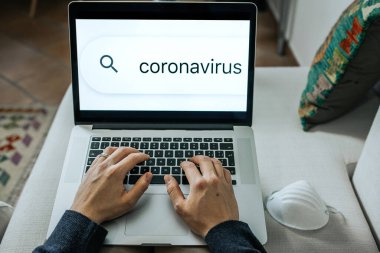 Üst görüşlü adam dizüstü bilgisayarda yazı yazıyor. Coronavirus salgını sırasında evde çalışıyor. Sahte haber ya da bilgi kavramı.