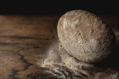 Un ve siyah arkaplanlı ahşap masada koyu çavdar ekmeği ile kapayın. Metin için solda boş alan.