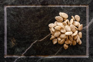 Sabun taşı yüzeyinde beyazlatılmış bademlerin üst yakın görüntüsü. Metin için boş alan.