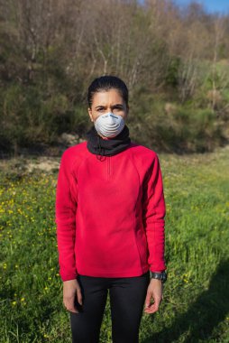 Açık havada spor aktiviteleri yapan koruyucu maskeli bir kadın portresi. Coronavirus ve sağlıklı yaşam tarzı konsepti.