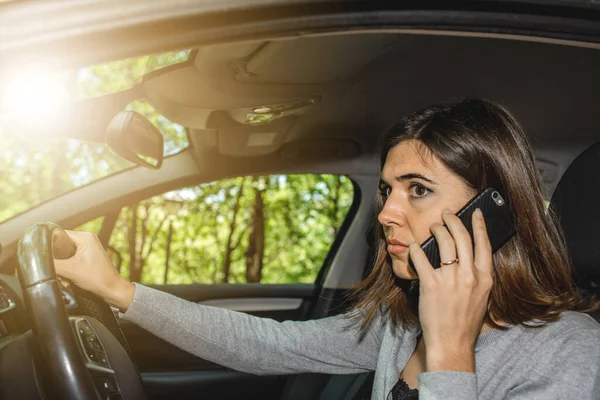 Araba kullanan genç bir kadının portresi bir trafik kazasına yol açmak için cep telefonuyla mesajlaşırken ve konuşurken. Hücum.
