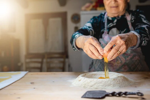 Mutfağındaki tahta kesme tahtasına hamur yoğuran yaşlı kadının portresi. Geleneksel yemekleri hazırlıyorum. Taze ev yapımı makarna.