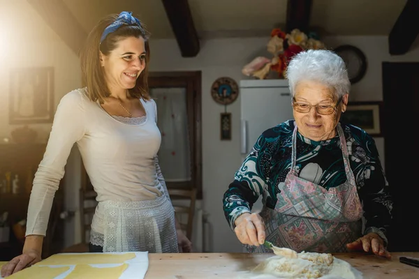 Büyükanne ve torunun birlikte yemek pişirirken gülümseyen portresi ev yapımı taze makarna..