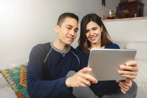 Kafkasyalı genç çift video görüşmesi için tablet bilgisayar kullanıyor. Evdeki kanepede oturan aile ya da arkadaşlarla konuşmak..