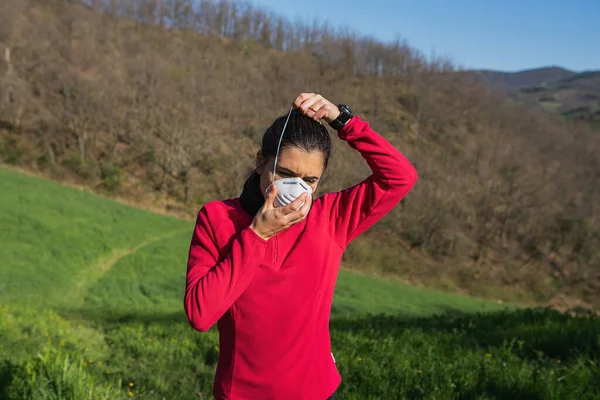 Dışarıda koşan genç bir kadın Coronvirus için yüz koruyucu maske takıyor. Spor ve salgın konsepti.
